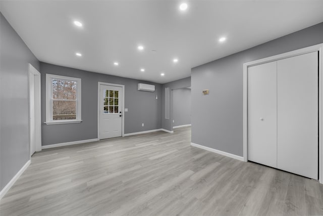 foyer entrance with an AC wall unit and light hardwood / wood-style floors