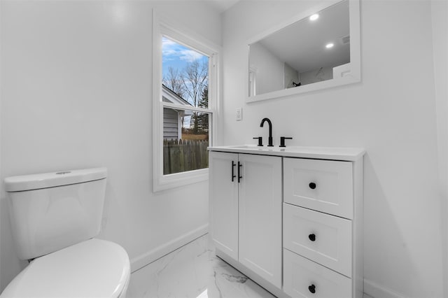 bathroom with toilet, vanity, and plenty of natural light