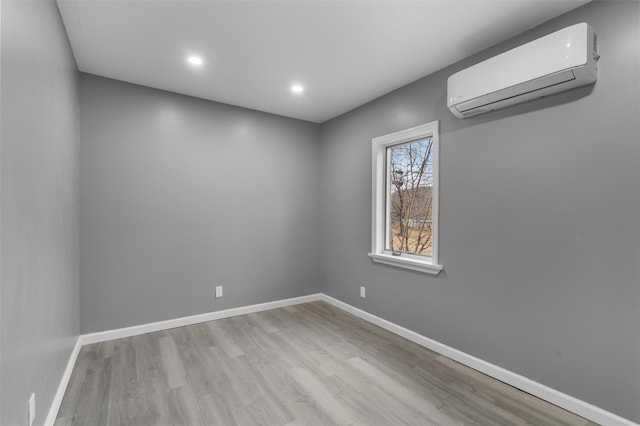 unfurnished room with light wood-type flooring and a wall mounted air conditioner