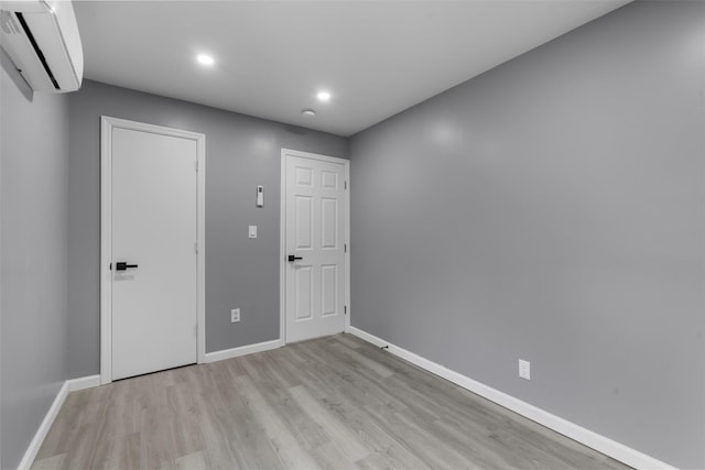 spare room featuring a wall mounted air conditioner and light hardwood / wood-style flooring