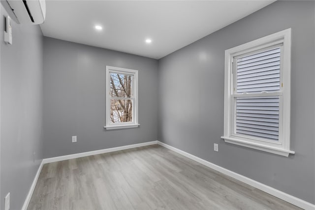 empty room featuring a wall mounted air conditioner and light hardwood / wood-style flooring