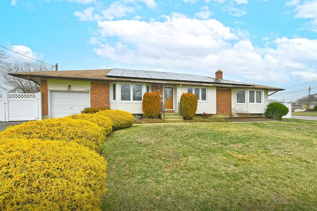 ranch-style home featuring solar panels, a garage, and a front lawn