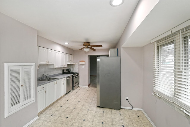 kitchen featuring ceiling fan, sink, stainless steel appliances, backsplash, and white cabinets