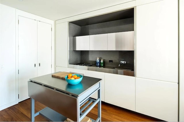 kitchen with white cabinetry, sink, dark hardwood / wood-style floors, backsplash, and stainless steel gas stovetop