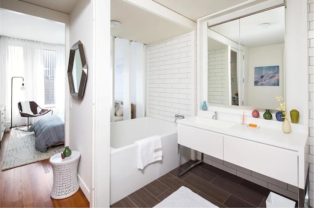 bathroom featuring wood-type flooring, vanity, and a tub