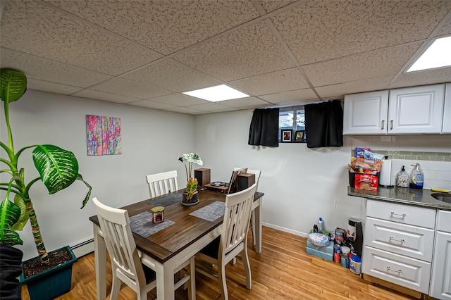 dining room with light wood-type flooring and a baseboard heating unit