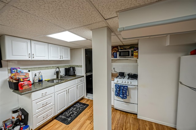 kitchen with a drop ceiling, decorative backsplash, sink, white appliances, and white cabinetry