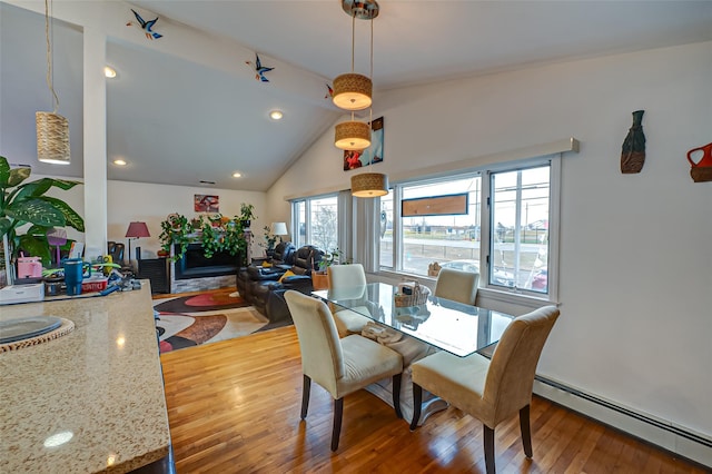 dining space featuring a baseboard heating unit, lofted ceiling, and hardwood / wood-style flooring