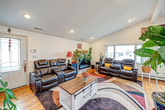 living room featuring baseboard heating, a wealth of natural light, lofted ceiling, and light hardwood / wood-style flooring