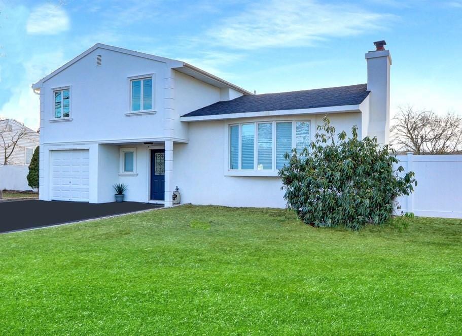 split level home featuring a garage and a front lawn