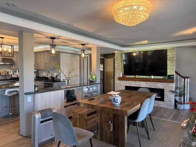 dining area featuring sink, a fireplace, light hardwood / wood-style floors, and a notable chandelier