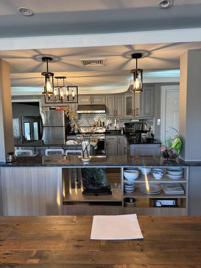 kitchen featuring stainless steel refrigerator, gray cabinetry, dark stone countertops, and pendant lighting