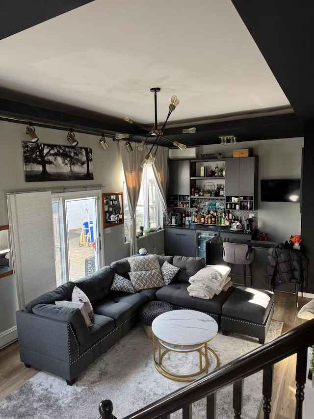 living room featuring plenty of natural light, indoor bar, a chandelier, and hardwood / wood-style floors