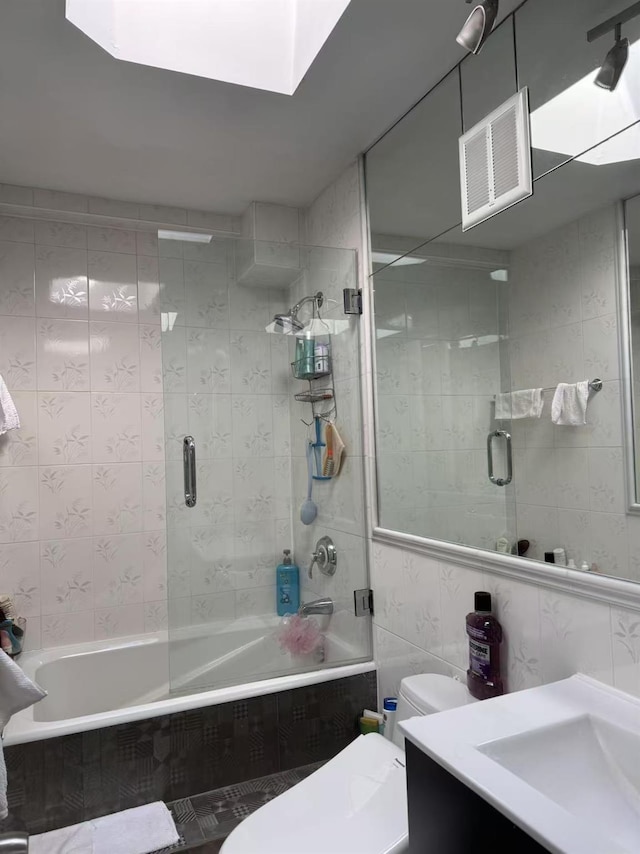 full bathroom with tile walls, toilet, vanity, and tiled shower / bath