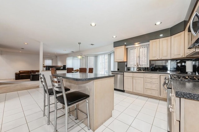 kitchen featuring a center island, light tile patterned floors, a breakfast bar area, hanging light fixtures, and appliances with stainless steel finishes