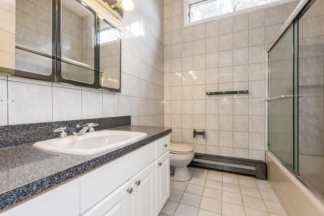 full bathroom with toilet, combined bath / shower with glass door, tile walls, a baseboard heating unit, and tile patterned floors