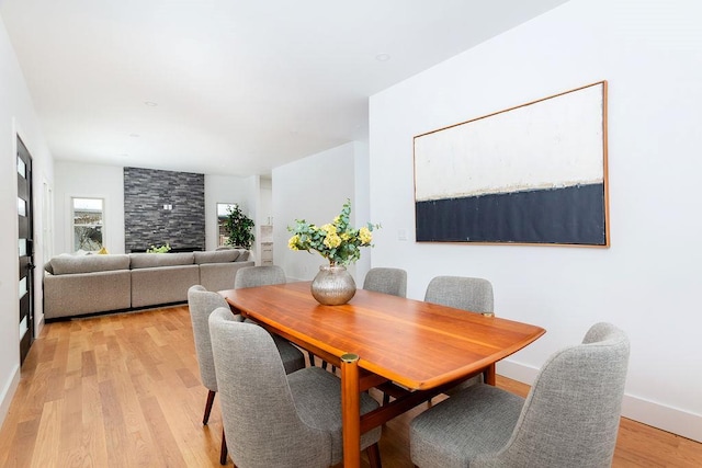 dining room with light hardwood / wood-style floors and a large fireplace