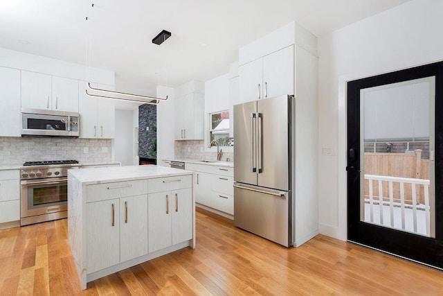 kitchen featuring high quality appliances, white cabinetry, and sink