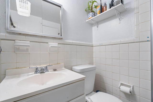 bathroom featuring vanity, tile walls, and toilet