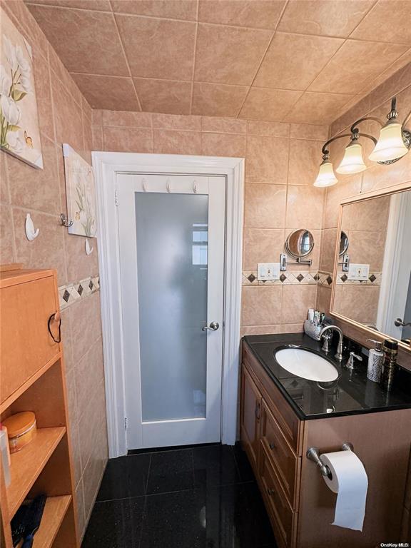 bathroom featuring vanity and tile walls