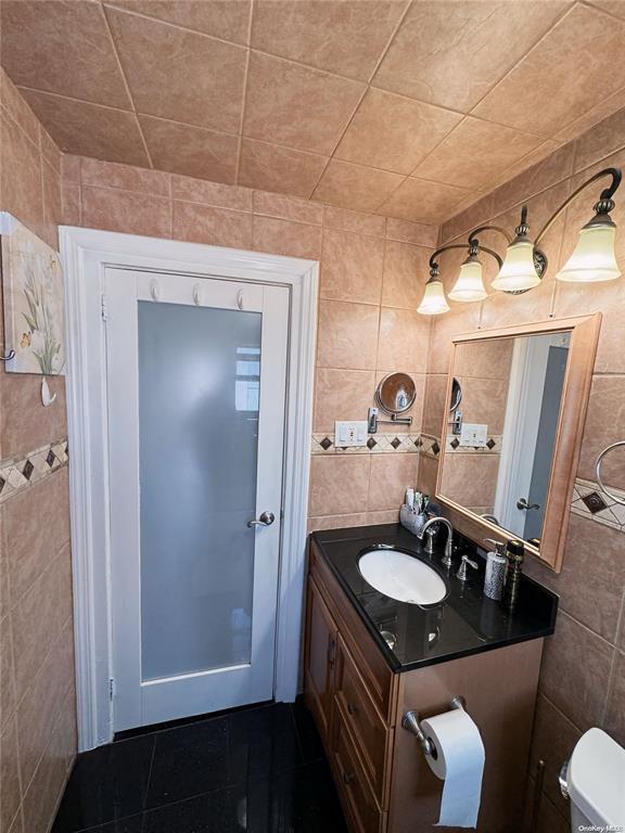 bathroom with vanity, tile walls, and toilet