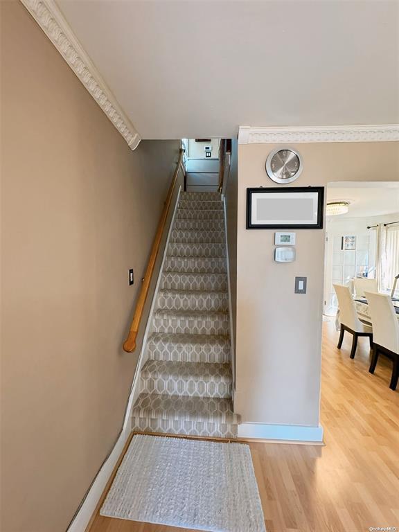 stairway featuring hardwood / wood-style floors and ornamental molding