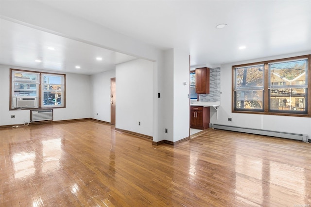 unfurnished living room featuring light hardwood / wood-style floors, baseboard heating, and cooling unit