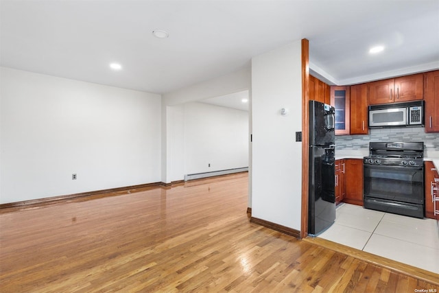 kitchen featuring backsplash, light hardwood / wood-style flooring, a baseboard heating unit, and black appliances