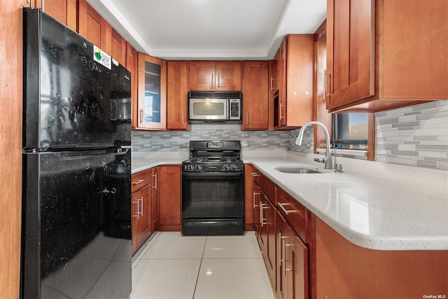 kitchen with backsplash, sink, light tile patterned flooring, and black appliances