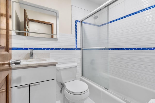 full bathroom featuring vanity, enclosed tub / shower combo, tile walls, and toilet