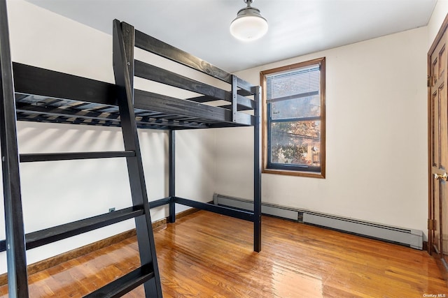 unfurnished bedroom with baseboard heating and light wood-type flooring