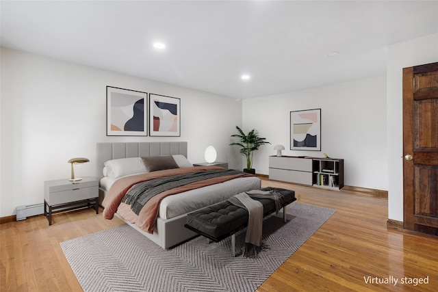 bedroom with baseboard heating and light hardwood / wood-style flooring