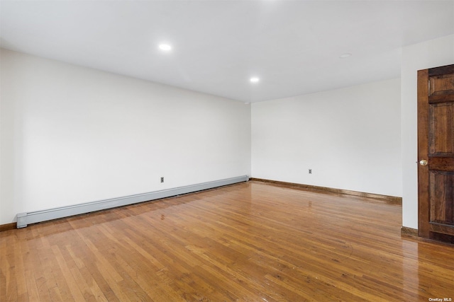 unfurnished room featuring a baseboard radiator and light hardwood / wood-style floors