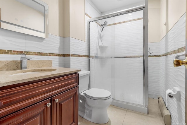 bathroom with baseboard heating, tile patterned floors, vanity, a shower with shower door, and tile walls