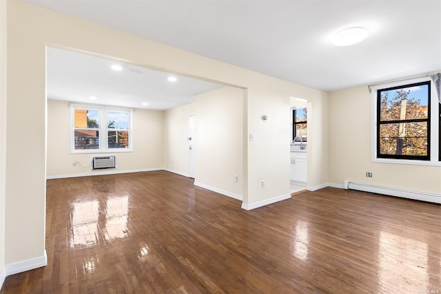 unfurnished living room featuring baseboard heating, a wealth of natural light, and dark hardwood / wood-style floors