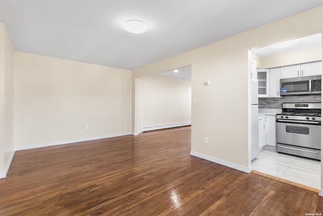 kitchen with white cabinets, decorative backsplash, light wood-type flooring, appliances with stainless steel finishes, and a baseboard radiator