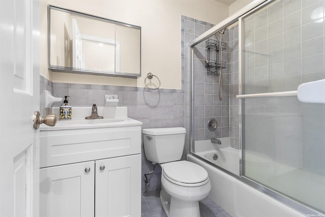 full bathroom with vanity, tile patterned flooring, toilet, enclosed tub / shower combo, and tile walls