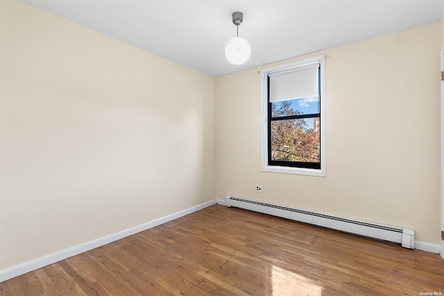 spare room with hardwood / wood-style floors and a baseboard heating unit