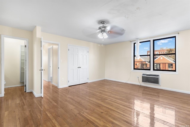 unfurnished bedroom featuring ceiling fan, wood-type flooring, a wall unit AC, and heating unit