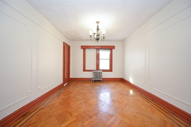 spare room featuring light parquet flooring, an inviting chandelier, and radiator