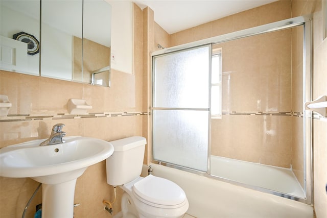 full bathroom featuring combined bath / shower with glass door, tasteful backsplash, sink, tile walls, and toilet