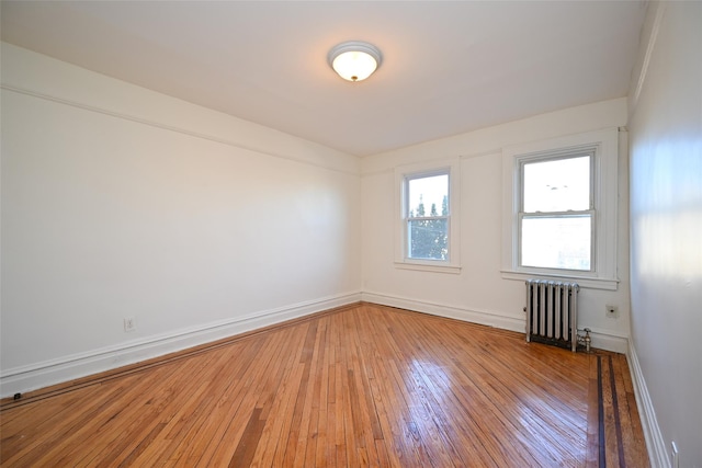 empty room with hardwood / wood-style flooring and radiator heating unit