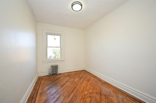 unfurnished room featuring radiator heating unit and hardwood / wood-style flooring