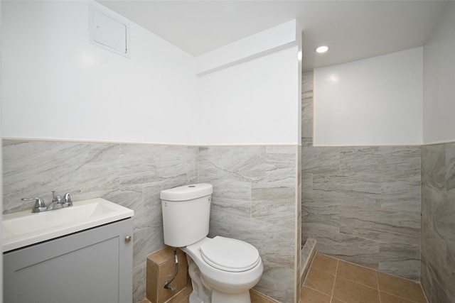 bathroom with tile patterned floors, vanity, tile walls, and toilet