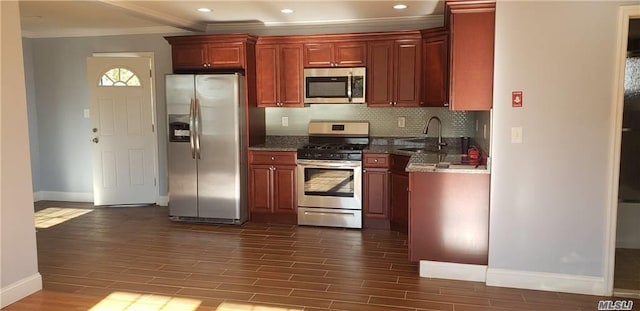 kitchen featuring sink, stainless steel appliances, tasteful backsplash, dark stone counters, and ornamental molding