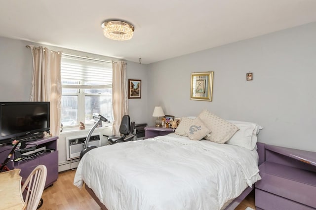 bedroom featuring light wood-type flooring, a wall unit AC, and baseboard heating