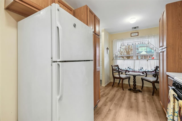 kitchen featuring white fridge, light wood-type flooring, and range