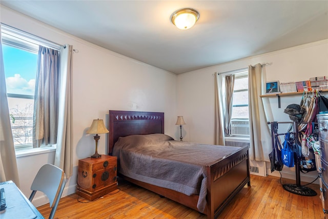 bedroom with hardwood / wood-style floors, radiator heating unit, and cooling unit