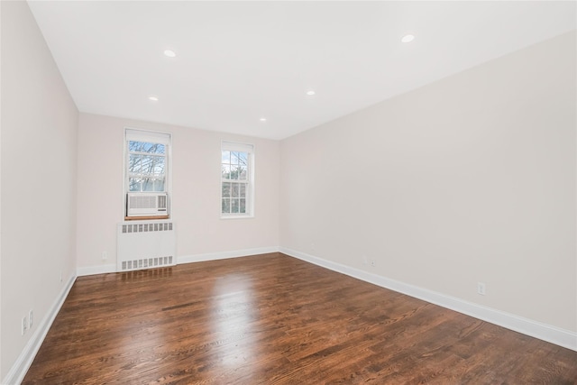 unfurnished room featuring dark hardwood / wood-style flooring, cooling unit, and radiator heating unit