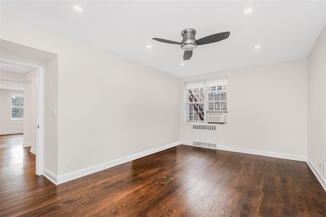 spare room with dark wood-type flooring, ceiling fan, cooling unit, and radiator heating unit